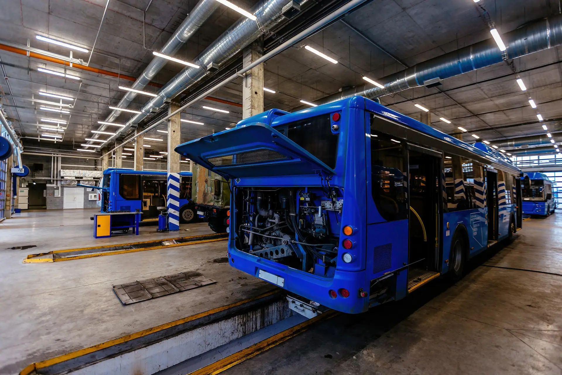 Avoid Unexpected Downtime with Proactive Battery Monitoring Blue electric bus in a maintenance bay with the engine compartment open, representing fleet battery health monitoring and maintenance.