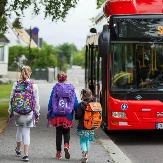 Tenix Value: Built on Trust Children with backpacks walking behind a red bus, symbolizing the Built on Trust value and reliable service.